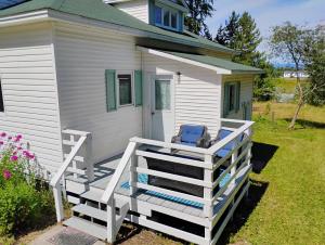 a white house with a porch with a chair on it at 6 Olivia Lane in Deer Lake