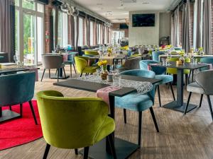 a restaurant with tables and colorful chairs and tables and chairs at Hotel Malinowski Leśny in Gliwice