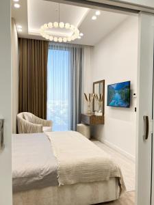 a bedroom with a bed and a chair and a window at Апарт-отель Urban Luxe Nest one Sky-High Luxury in Tashkent