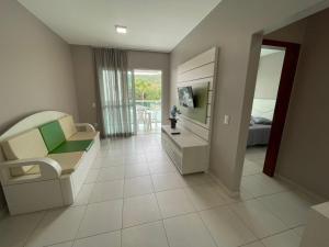 a living room with a couch and a television in a room at cód 36 · Apartamento a 80 metros do mar com sacada in João Neiva