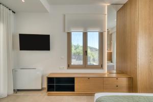 Un dormitorio con una cama, un espejo y un televisor. en Elena's Sunset Villa, en Piryiótika 69 fotos más