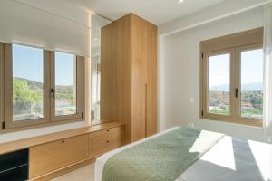 Un dormitorio con una cama y dos ventanas. en Elena's Sunset Villa, en Piryiótika