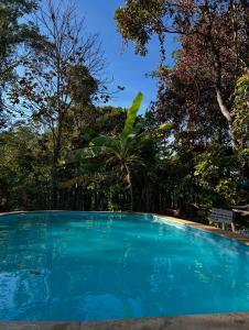 Una piscina azul con árboles al fondo. en Camping do Caminho- Suites, en Pirenópolis