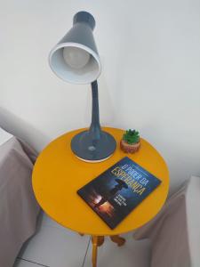 a book on a table with a lamp and a lamp at STUDIO URBANO Ar Garagem 2 Quartos in Petrolina