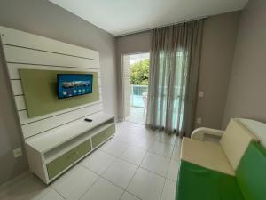 Una sala de estar con un televisor en la pared. en cód 39 · Apartamento com vista mar, en Governador Celso Ramos