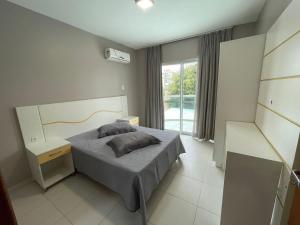 Un dormitorio con una cama y un escritorio y una ventana. en cód 39 · Apartamento com vista mar, en Governador Celso Ramos 14 fotos más
