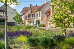 a garden with purple flowers in front of houses at Central Odense Hideaway – Courtyard Apartment in Odense