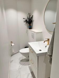 a white bathroom with a toilet and a sink at Central Odense Hideaway – Courtyard Apartment in Odense +20 photos