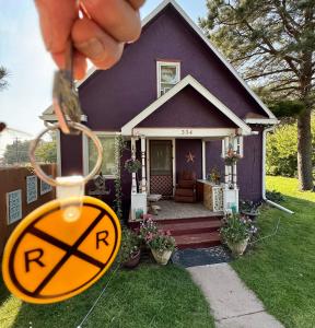 a person holding a sign in front of a house at 1912 Nostalgic TrainCrew Boarding House in Potter