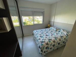 a bedroom with a bed with a floral bedspread and a window at Cód 56 · Apartamento amplo bem equipado in Governador Celso Ramos +38 photos