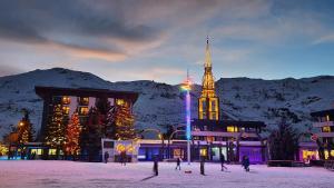 a building with a clock tower in the snow at night at Les Menuires sur les pistes in Les Menuires