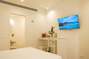 Un dormitorio con una cama y un televisor en la pared. en Emma's Downtown - Eco Design Rooms, en Olbia
