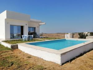 a swimming pool in front of a house at Petite villa- Tamezrat- Kelibia in Kelibia