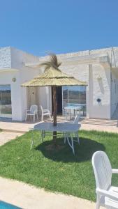 a table with a straw umbrella in the grass at Petite villa- Tamezrat- Kelibia in Kelibia