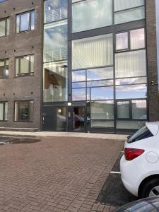 a white car parked in front of a building at Cozy Studio Apartment Near Heathrow Airport Terminal 4 - Unlimited Wi-Fi - Paid Parking in New Bedfont