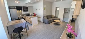 a kitchen and living room with a couch and a table at Escapade Pau Appart moderne avec terrasse privée in Pau