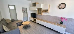 a living room with a couch and a clock on the wall at Escapade Pau Appart moderne avec terrasse privée in Pau