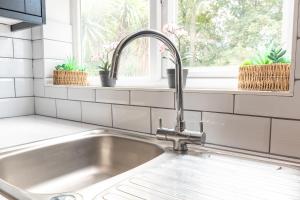 eine Küchenspüle mit einem Wasserhahn neben einem Fenster in der Unterkunft KGV Stays - Serenity House 3 bedroom near to the hospital with parking in Southampton + 43 Fotos