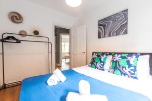 ein Schlafzimmer mit einem blauen Bett mit Handtüchern darauf in der Unterkunft KGV Stays - Serenity House 3 bedroom near to the hospital with parking in Southampton