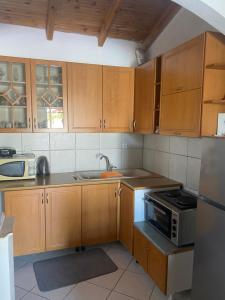 a kitchen with wooden cabinets and a sink and a microwave at Rosemary House in Sarandë +46 photos