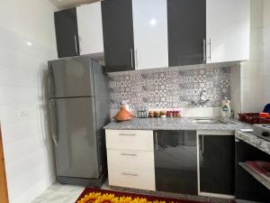 a kitchen with a stainless steel refrigerator and white cabinets at Spacious 3BR Apartment Near Akdital in Fès +9 photos