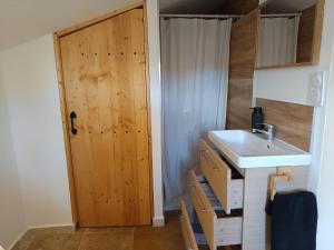 a bathroom with a sink and a wooden door at Le Nid Douillet in Arles