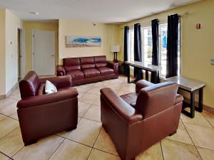 a living room with brown leather furniture and a piano at Put-in-Bay Poolview Condo #3 in Put-in-Bay