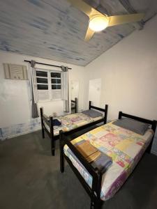 a bedroom with two beds and a ceiling fan at Suites por do Sol in Búzios +16 photos