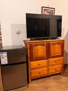 a television on top of a wooden dresser with a refrigerator at Wayra del Cerro in Purmamarca