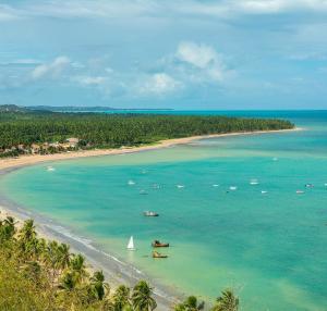 an aerial view of a beach with boats in the water at Jangadeiro Suítes in Japaratinga
