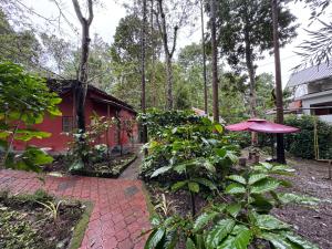 une maison rouge avec un parapluie rouge et quelques plantes dans l'établissement Manuvan home stay ac cottage, à Kushalanagar