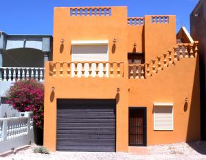 an orange building with a garage door and stairs at Casa Arco Iris in La Choya