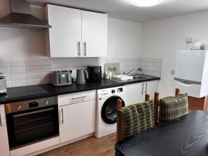 a kitchen with white cabinets and a washing machine at Cottage style flat in Oswaldtwistle