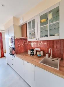 a kitchen with white cabinets and a sink at L'Échappée Bleue, maison à 200m de la mer pour vacances et travail in Saint-Brevin-les-Pins