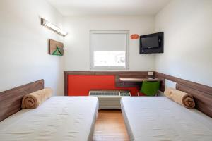 a small room with two beds and a desk at Hotel Hi! Zapopan in Guadalajara
