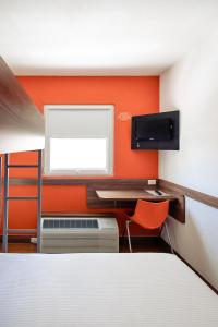 Un dormitorio con paredes naranjas y un escritorio y una ventana. en Hotel Hi! Zapopan, en Guadalajara