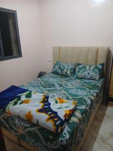 een bed met een deken en kussens erop bij Zina résidence in Aourir