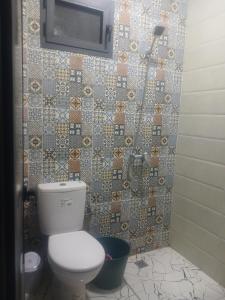 een badkamer met een toilet en een tv aan de muur bij Zina résidence in Aourir
