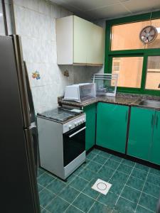 Una cocina con gabinetes verdes y una estufa. horno superior en Modern Comfort Stay, en Sharjah