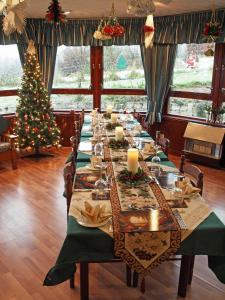 a long table in a room with a christmas tree at Achnabobane Farmhouse in Spean Bridge