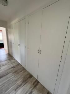 a row of white closets in a room with wood floors at Maison BERDOT in Sévignac-Thèze