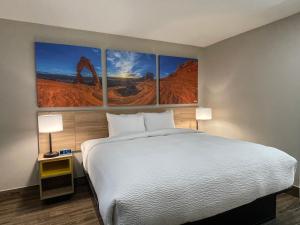1 dormitorio con 1 cama con 4 cuadros en la pared en Days Inn by Wyndham Sulphur Springs, en Sulphur Springs