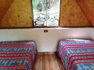 two beds in the corner of a room with a window at Lucmabamba Cottage in Sahuayacu