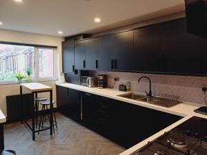 a kitchen with black cabinets and a sink at Exclusive private rooms in great houseshare in Liverpool