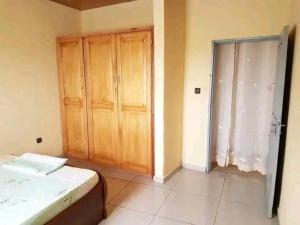 a bedroom with a bed and wooden cabinets and a window at Studio Ydé Bastos in Yaoundé