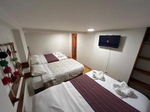 クスコにあるAndean charm Aparts & Roomsのベッド2台と薄型テレビ付きのホテルの部屋