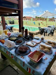 a table with food on it in front of a pool at Pousada Aconchego de Maricá in Maricá