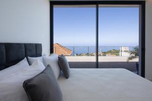 ein Schlafzimmer mit einem Bett mit Blick auf den Strand in der Unterkunft A&M House III in Arco da Calheta + 21 Fotos