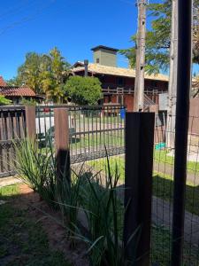 a fence with plants in front of a house at Residencial Casa Laranja - Casas na Praia da Ferrugem in Garopaba