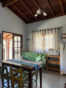 a living room with a table and a green couch at Residencial Casa Laranja - Casas na Praia da Ferrugem in Garopaba